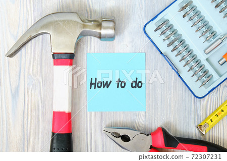 How to do concept on a sheet of paper next to work tools on wooden background How to do concept on a sheet of paper next to work tools on wooden background 72307231