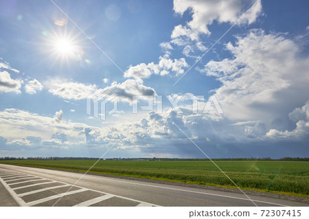 Asphalt highway with road markings on the background of blue sky and clouds Asphalt highway with road markings on the background of blue sky and clouds 72307415