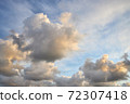 Fluffy clouds backlit by the sun at sunset 72307418