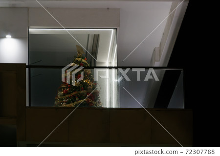 Decorated Christmas lit tree with ornaments at a building balcony. Decorated Christmas lit tree with ornaments at a building balcony. 72307788