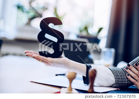 Woman hand holding wooden black paragraph the symbol of law and justice Woman hand holding wooden black paragraph the symbol of law and justice 72307870