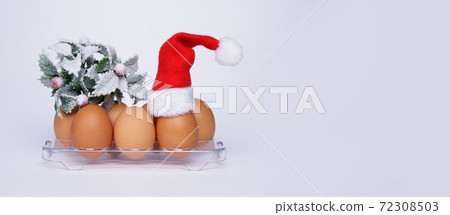chicken eggs tray with sprig of Christmas tree and on one of the eggs Santa hat chicken eggs tray with sprig of Christmas tree and on one of the eggs Santa hat 72308503