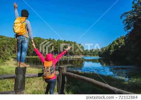 Couples travelers with backpack happy to relax on a holiday, travelers Pang-Ung park travel,Travel to visit nature landscape the beautiful at lake, at Mae-hong-son, in Thailand. Couples travelers with backpack happy to relax on a holiday, travelers Pang-Ung park travel,Travel to visit nature landscape the beautiful at lake, at Mae-hong-son, in Thailand. 72312864