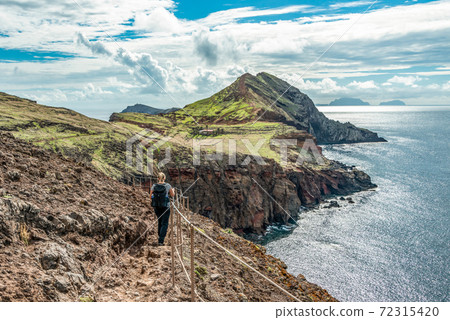 Girl hiking rocky cliffs clear near water of Atlantic Ocean bay Ponta de Sao Lourenco, the island of Madeira, Portugal 72315420