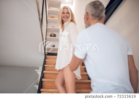 Woman holding mans hand and going upstairs Woman holding mans hand and going upstairs 72315619
