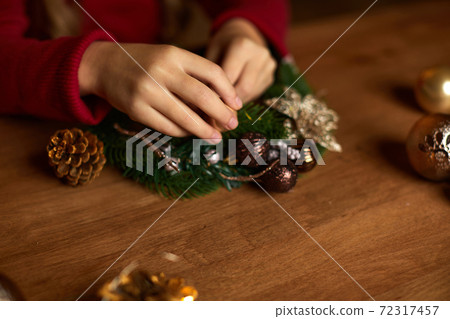 little child girl makes a handmade Christmas wreath 72317457