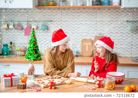 Little girls making Christmas gingerbread house at fireplace in decorated living room. 72318672