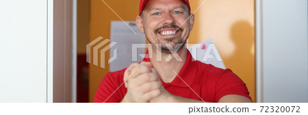 Courier in red uniform smiles and greets client 72320072