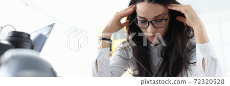 Woman sits with her eyes closed and holds her head in office. Woman sits with her eyes closed and holds her head in office. 72320528