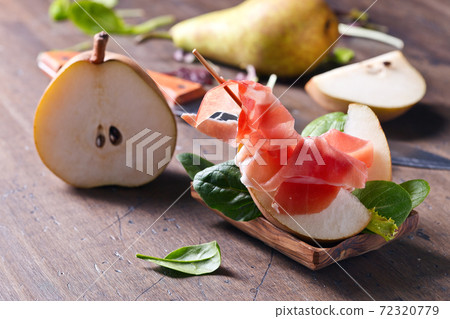 prosciutto with pear on a wooden table prosciutto with pear on a wooden table 72320779