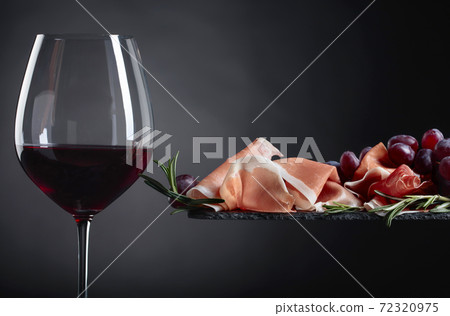 Prosciutto with rosemary and glass of red wine. Prosciutto with rosemary and glass of red wine. 72320975
