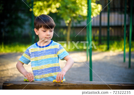 Cute little boy, playing with little toy cars on the street on sunset, summertime 72322235