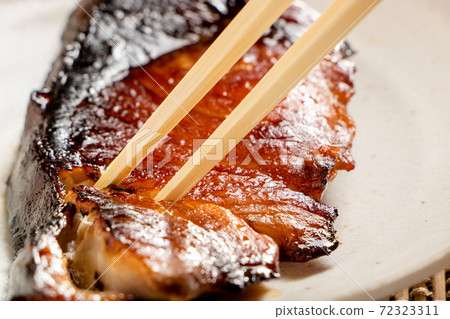 Grilled fish (teriyaki yellowtail) and chopsticks. 72323311