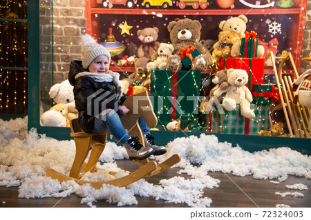 Happy child riding rocking horse near toy shop 72324003