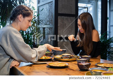 Two girlfriends chatting and having some snacks in a cafe 72324465