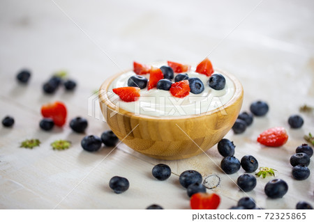 Bowl filled with yoghurt and berries on white table 72325865