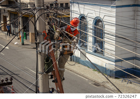 Men repairing electrical grid wires using masks because of COVID-19 72326247