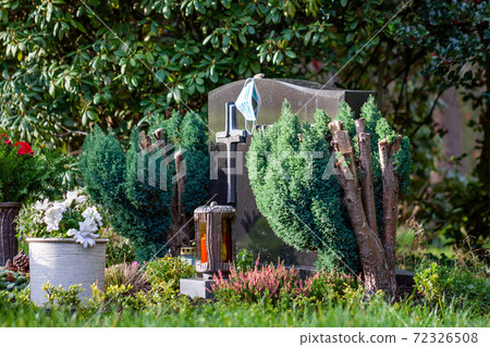 Facemask lying on grave of family members with a facemask during the pandemic 72326508