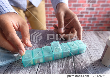 man's hands taking medicine from a pill box man's hands taking medicine from a pill box 72326950