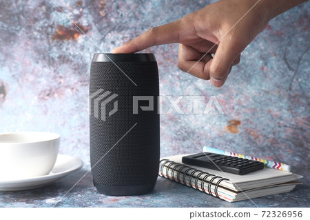 man's hand using smart speaker on table  72326956