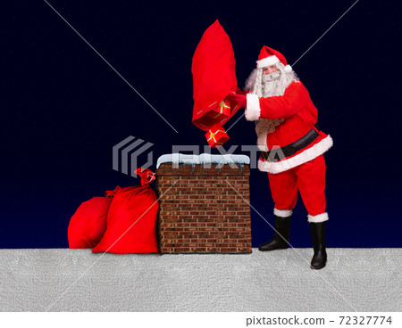 Santa Claus standing at a snowy roof and throw gifts from bag into the chimney-  72327774