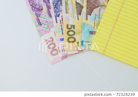 Ukrainian money grivna with banknotes on yellow notebook write in white background 72328239