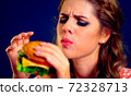 Woman eating hamburger. Appetizing face of girl happy eat junk . 72328713