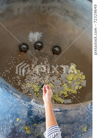 A Buddhist tradition - throwing a coin and paper wish to a large pot for hope be wealth and lucky  72329649