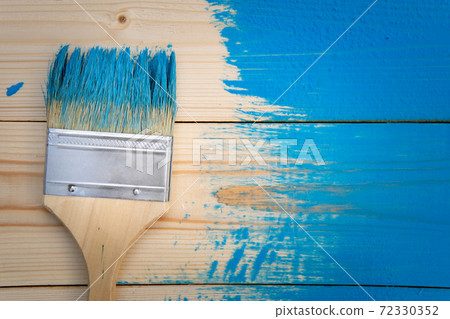 Painting works background with paintbrush in blue paint on the wooden not completely painted boards 72330352