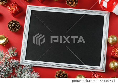 New Year's frame with New Year's toys, fir branches and gifts in an environment on a red background. New Year's frame with New Year's toys, fir branches and gifts in an environment on a red background. 72330751