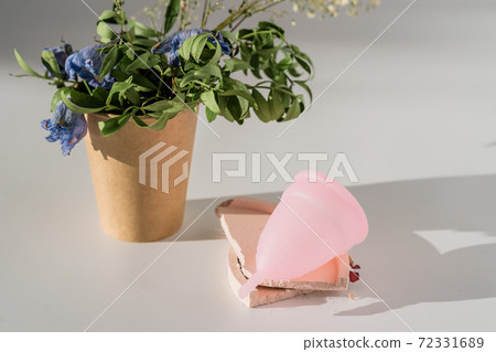 pink menstrual cup with flowers on white background with sunlight and shadows 72331689