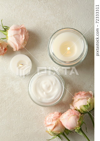 Scented candles, cosmetic cream and roses on white table 72333311