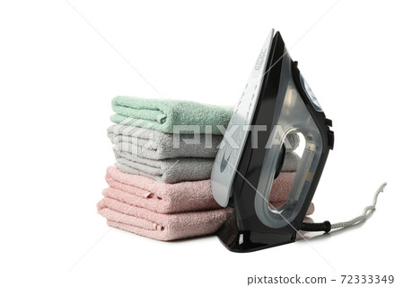 Iron and pile of towels isolated on white background Iron and pile of towels isolated on white background 72333349
