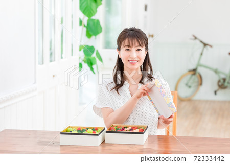 Woman opening the lid of a fruit jewelry box 72333442