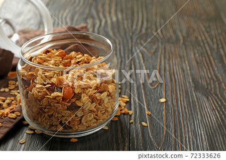 Glass jar with tasty granola on wooden background Glass jar with tasty granola on wooden background 72333626
