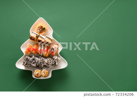 Sushi set in plate as Christmas tree decorated fir tree branches on green. 72334206