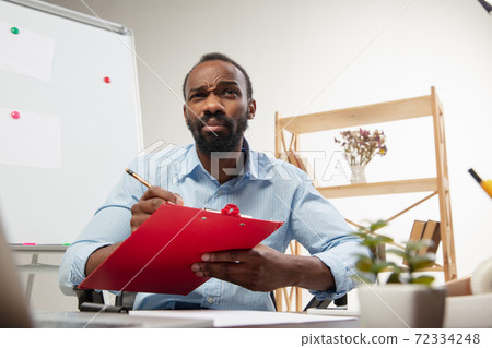 Online english courses at home. Smiling man teaches students remotely in interior of living room 72334248