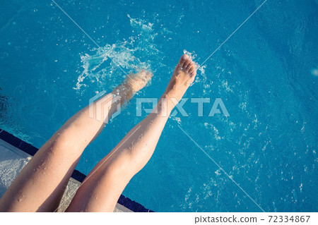 cropped young european woman kicks in the pool splashes water. Concept, carefree, summer, vacation cropped young european woman kicks in the pool splashes water. Concept, carefree, summer, vacation 72334867