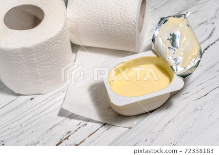 Pack of yogurt with tiolet paper on white wooden desk. 72338183