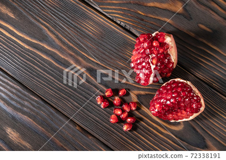 Craked ripe pomegranate on dark wooden background Craked ripe pomegranate on dark wooden background 72338191