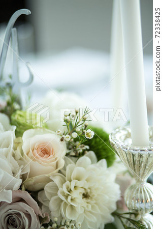 Wedding table setting is decorated with fresh flowers and white candles. Wedding floristry. Bouquet with roses, hydrangea and eustoma. Table numbering Wedding table setting is decorated with fresh flowers and white candles. Wedding floristry. Bouquet with roses, hydrangea and eustoma. Table numbering 72338425