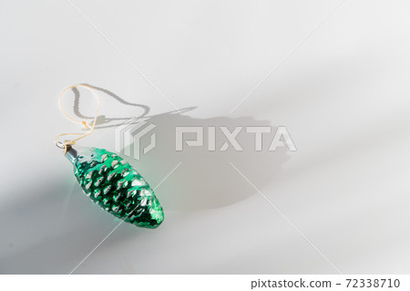 Green pine cone glass vintage christmas bauble on white background with sunlight and shadow 72338710
