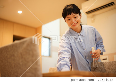A woman wiping a table 72341048