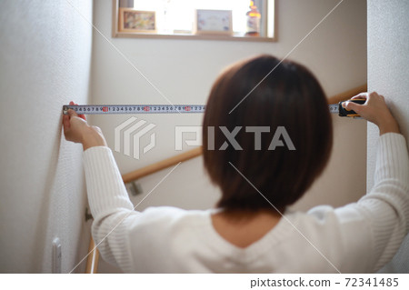 Woman measuring the width of the stairs Woman measuring the width of the stairs 72341485