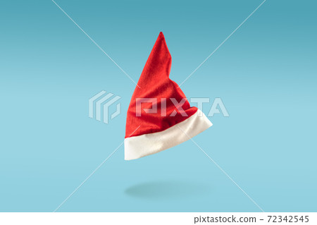 Santa Claus hat levitation on blue background. Minimal Christmas concept. Flying cap in the air Santa Claus hat levitation on blue background. Minimal Christmas concept. Flying cap in the air 72342545