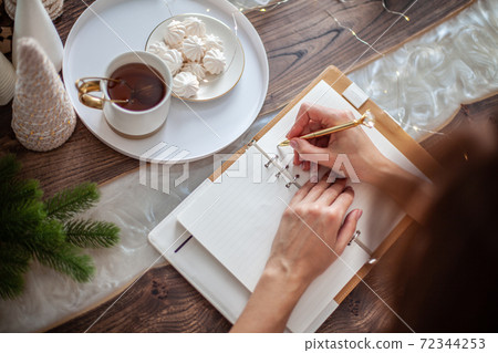 Young woman writing plans or goals for New Year 2021 while her daughter crafting Christmas trees Young woman writing plans or goals for New Year 2021 while her daughter crafting Christmas trees 72344253