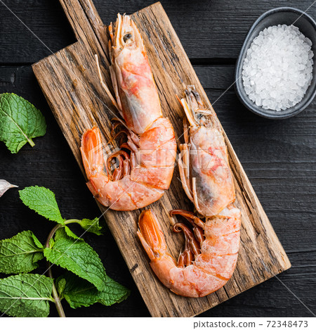 Seafood scampi on wooden board on black wooden background, flat lay Seafood scampi on wooden board on black wooden background, flat lay 72348473