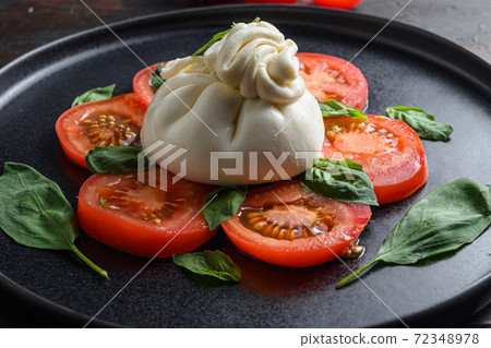 Handmade burrata cheese served with fresh tomatoes Handmade burrata cheese served with fresh tomatoes 72348978