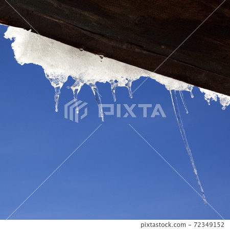 Wooden roof with snow cornice and icicles at sun winter day 72349152