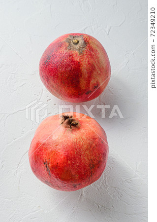 Fresh pair of pomegranate over white concrete Fresh pair of pomegranate over white concrete 72349210